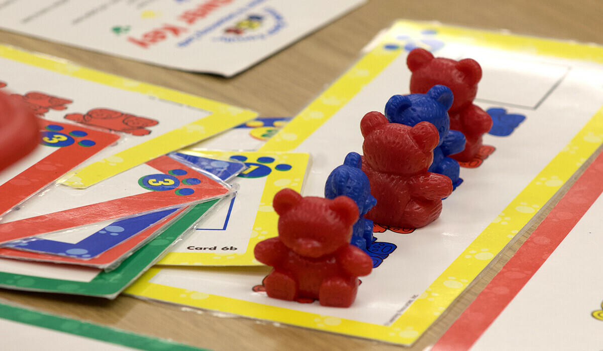 School work on a table under a row of red and blue small bears.